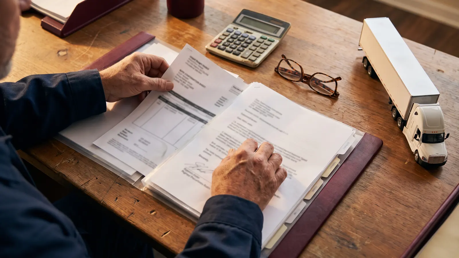 Broker nonpayment and bond claims Trucking company owner organizing invoices and a bond claim packet at a desk